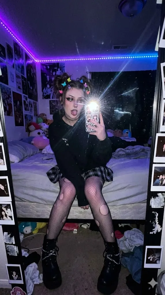 Девушка E-Girl фотографируется в зеркале в спальне с LED-подсветкой.