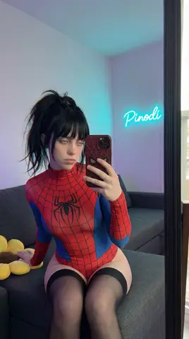 Женщина в костюме Spider-Man сидит на диване и фотографируется в зеркале.