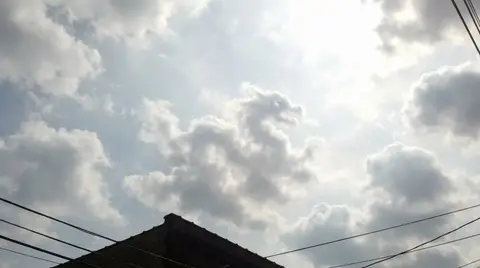 Зернистый снимок облачного неба с бесформенной тучей, которая слегка напоминает заданный объект.