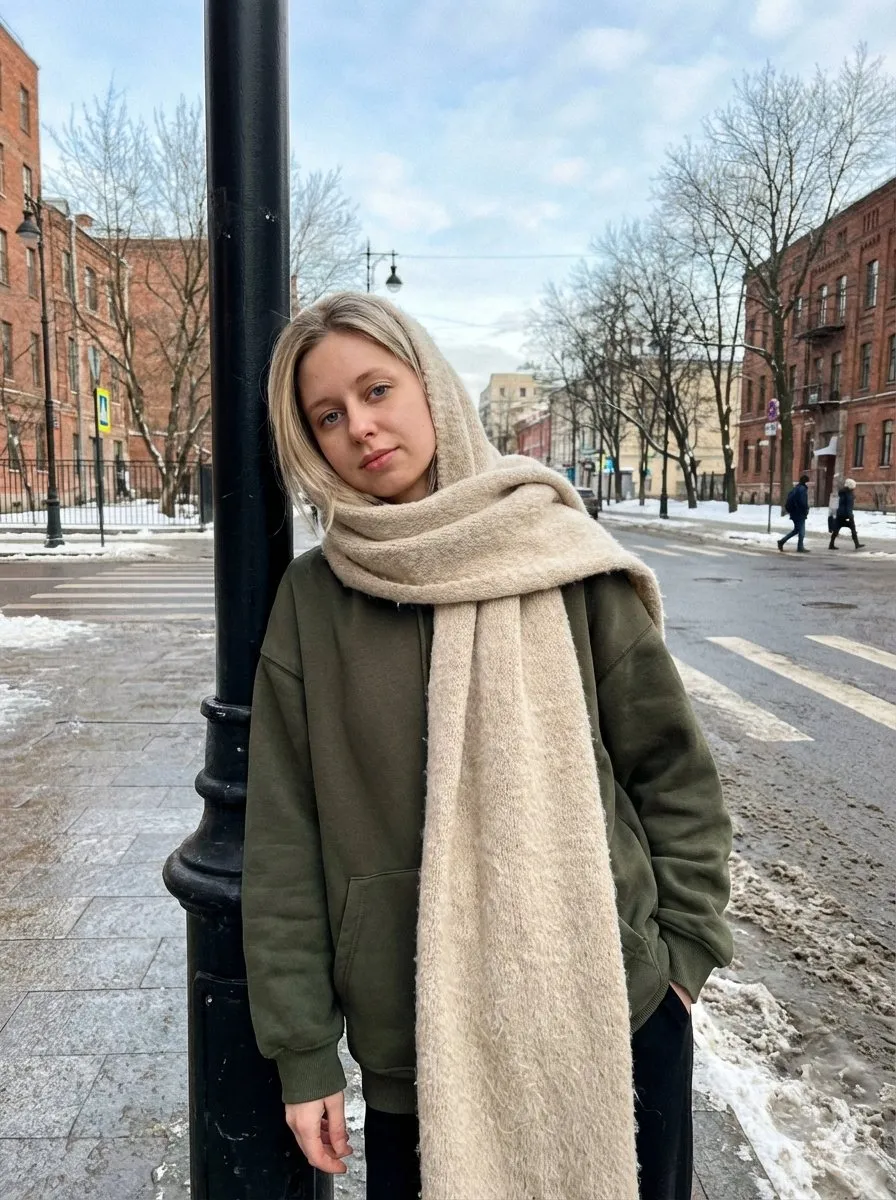 Мужчина в оливковой толстовке и бежевом шарфе стоит у фонаря на зимней улице. · пример 2