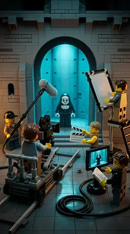 Минифигурка монахини стоит в каменной арке, вокруг неё LEGO-съёмочная группа и оборудование.