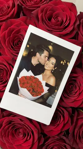 Снимок Polaroid с парой лежит на красных розах.