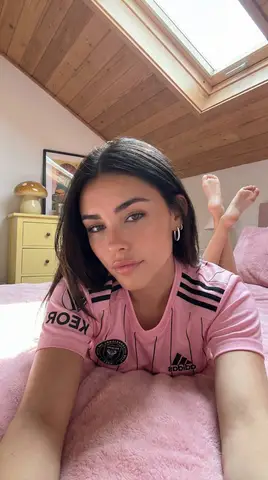Женщина в белой форме Adidas лежит на кровати в мансардной спальне