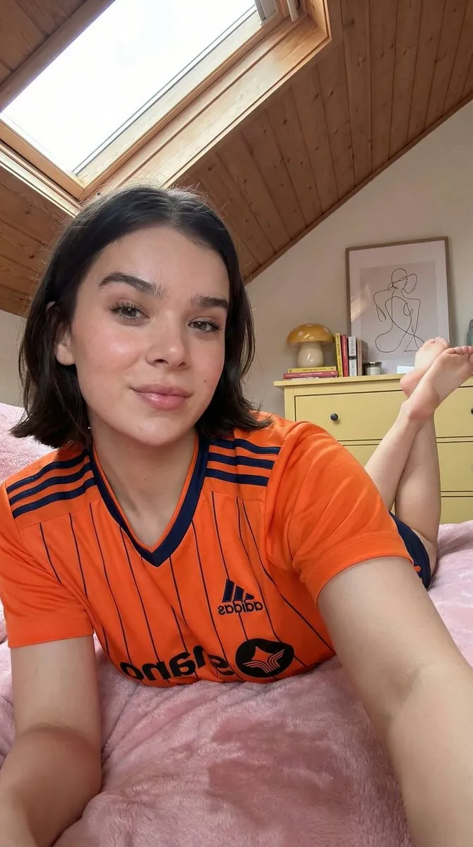 Женщина в белой форме Adidas лежит на кровати в мансардной спальне · пример 2
