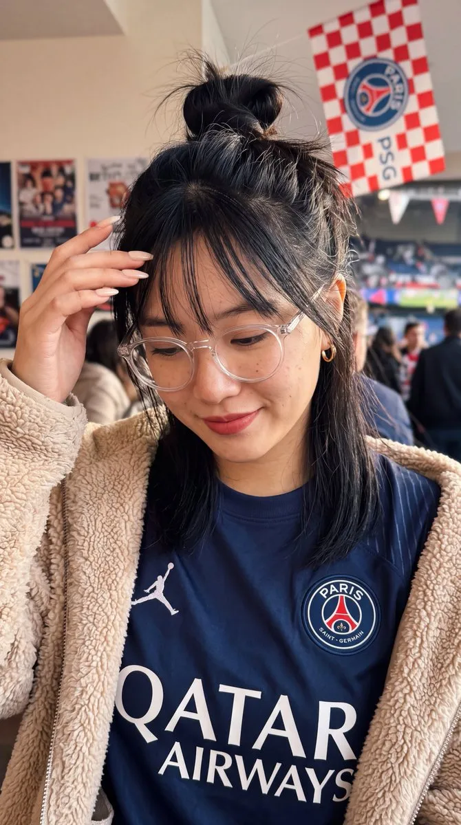 Женщина в джерси PSG и бежевой плюшевой куртке снимает селфи. · пример 2