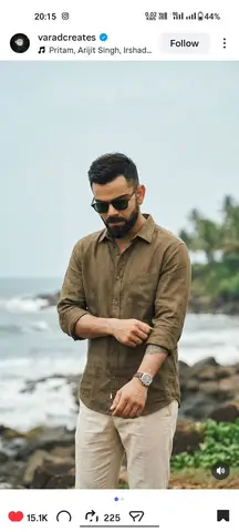 Virat Kohli стоит у скалистого морского берега в льняной рубашке и тёмных очках.