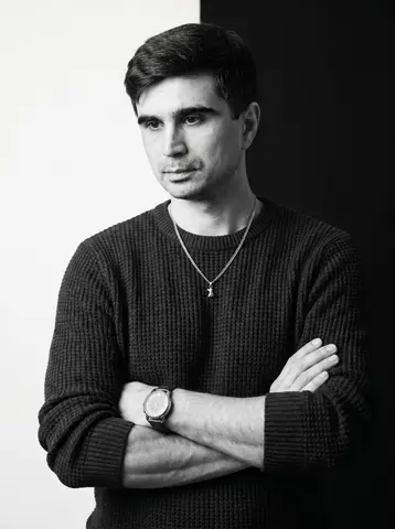 Пример к промпту: мужчина в тёмном фактурном свитере и с часами скрестил руки на фоне, разделённом на белую и чёрную половины.
